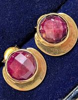 Front view of both ruby stud earrings set in gold-tone silver