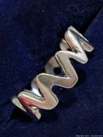Close-up of silver zigzag ring on dark fabric