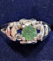 Front view of silver ring showing emerald and side stones