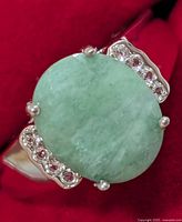 Front view of ring showing oval green center stone and accent stones