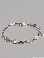 Full view of silver bracelet laid flat showing overall design and charms