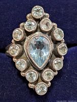 Top view of ring showing pear aquamarine center and halo of round stones