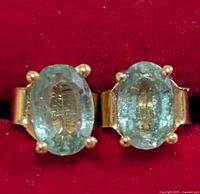 Front view of both stud earrings showing oval emeralds in prong settings