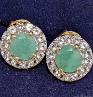 front view of earrings showing green centre stones and clear halo