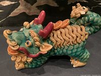 Side view of green ceramic dragon figurine displaying glaze colours and texture