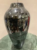 Front view of tall iridescent glass vase showing overall shape, finish, and surface decoration