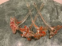Four handblown glass flower stems arranged on stone surface