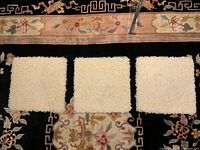 Three cream wool square mats on patterned background