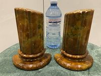 Pair of alabaster bookends beside water bottle for scale