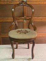 Front view of wooden chair with floral needlepoint seat