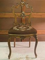 Front view of carved side chair showing ornate backrest and floral upholstered seat