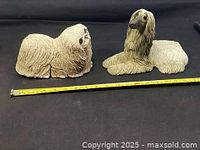 Two dog statues side by side with tape for scale