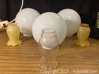 Front view of three white globe shades, two yellow tulip shades, one clear cylinder shade