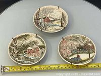 Three landscape ceramic plates with tape measure showing size
