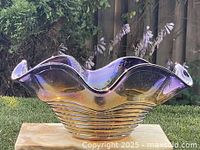 Front view of purple iridescent art glass bowl showing ruffled rim and ribbed body