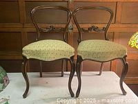 Front view of both mahogany side chairs showing upholstery and carved backs