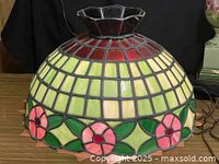 Side view of leaded stained glass shade showing floral border and color pattern