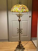 Full view of floor lamp showing base, stem and illuminated shade