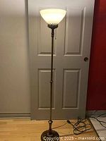 Full view of brass torchiere floor lamp with cord and base visible