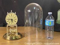 Clock, glass dome and water bottle for scale