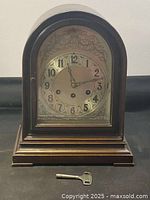 Front view of wood arch-top mantel clock and key