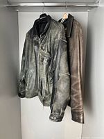 Two leather jackets hanging: Roots black leather and distressed black leather