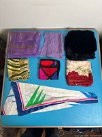 Seven scarves laid out showing colours and patterns