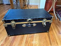 Overall view of navy blue cedar-lined trunk with brass hardware and leather side handles