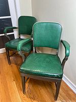 Two green vinyl metal arm chairs angled view