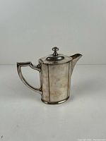 Right side view of silver plated coffee pot showing handle, spout, finial