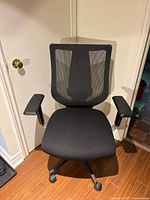 Front view of black mesh office chair with armrests