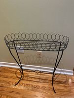 Full view of black metal plant stand against wall