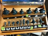Open wooden case displaying 15 router bits
