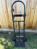 Front view of black steel hand truck showing handle, frame, pneumatic tires, footplate