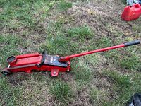 Full view of Motomaster hydraulic trolley jack with handle attached on grass
