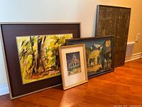 Four framed artworks leaning against wall showing relative sizes and subjects