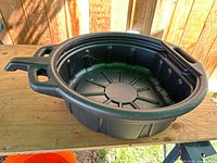 Top view of black plastic oil drain pan on work surface