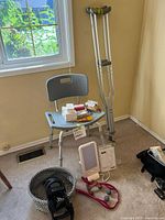 Full lot showing bath chair with soaps on seat, crutches, HappyLight lamp, basket, knee brace, massage strap