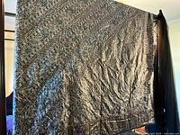 Full view of teal gold and black bedspread hanging