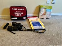 Binoculars, first aid kit, manuals, foot mask, flashlight grouped on floor