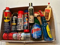 Box showing WD-40, NXT aerosol, Lepage cans, Drano, glass cleaners, glues