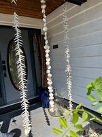 Full view of three shell garlands, blue vase with sticks, and clear glass jug