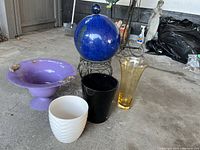 group shot of cobalt sphere on stand, purple vase, gold glass vase, black and white pots