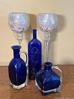 Group shot of all five items: two mosaic votive holders and three cobalt blue glass vessels