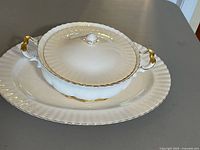 Covered vegetable bowl stacked on oval platter showing color, trim, shape