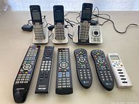 Overall lot: three VTech phones on bases with chargers and six assorted remotes laid out