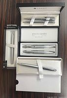 Overview of all boxed pen sets: Foray two-pen set, Sheaffer fountain pen package, Pierre Cardin two-pen set, Cross single pen