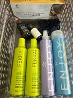 Overall lot in clear bin, showing Fekkai bottles, Enjoy cans, oil bottles, boxed cream
