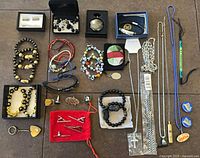 Overview of entire lot laid out showing bracelets, cufflinks, pocket watch, lanyards, keychain, pins and necklaces