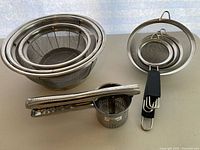 Group shot of all strainers, tongs, ricer and pronged utensil